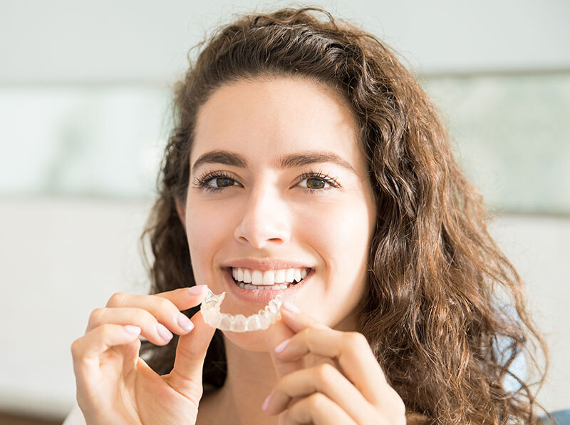 Adult woman with Invisalign aligners, smiling confidently after treatment